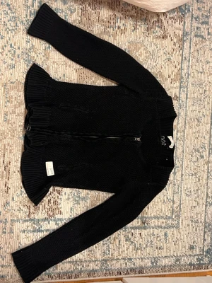 Svart stickad kofta med dragkedja - Snygg svart stickad kofta med dragkedja från Odd Molly. Koftan har lång ärm och en klassisk, enkel design som passar till det mesta. Perfekt för lager på lager och enkel att matcha.