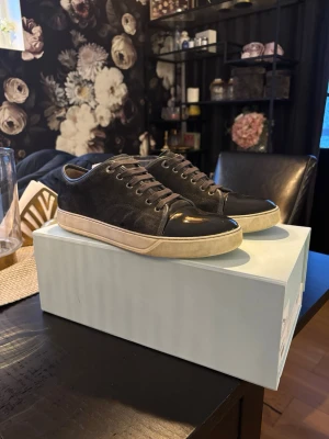 Svarta sneakers med mocka och läder - Snygga svarta sneakers med ovandel i mocka och tåparti i blankt läder. Skorna har vita sulor och svarta skosnören för en clean look. Perfekta för dig som gillar stilrena och klassiska sneakers med en twist.