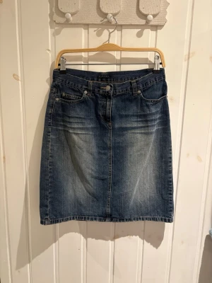 Blå jeanskjol med slits bak från SISLEY - Klassisk blå jeanskjol i rak modell med fem fickor och slits bak. 100% bomull. Står i kjolen att det är en 42a men skulle säga att det är en 40  (jag är en 38a och den passar nästan)