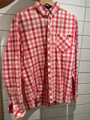 Rödvitrutig skjorta från Bondelid - Säljer en klassisk rödvitrutig skjorta från Bondelid. Skjortan har lång ärm, bröstficka med liten logga och knappar hela vägen. Tillverkad i mjuk bomull och perfekt för dig som gillar en avslappnad men snygg stil.