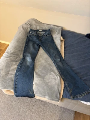 Blå bootcut jeans med utsvängda ben - Säljer ett par klassiska blå jeans med bootcut och utsvängda ben. Jeansen har fem fickor, normal passform och är tillverkade i ett tåligt denimtyg. Perfekta för dig som gillar retrovibbar och vill ha ett par jeans som sticker ut. Säljer pga att storleken är för stor