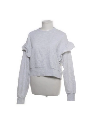 Grå sweatshirt med volangdetaljer - Trendig ljusgrå sweatshirt med volanger längs axlarna och ärmarna. Tröjan har rund halsringning, långa ärmar och ribbade muddar. Den är ifrån H&M i storlek M