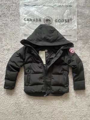 Canada goose black label - Säljer en stilren Canada Goose dunjacka i svart. Klassisk modell som passar perfekt för kalla vinterdagar varm, bekväm och tidlös.  ✔ Äkthet: Original, med originalpåse & tags ✔ Färg: Svart (svart badge) ✔ Skick: Mycket fint skick ✔ Detaljer: Huva, kraftig dragkedja, hög värmeisolering ✔ Passform: Modern och bekväm  En exklusiv vinterjacka av högsta kvalitet 
