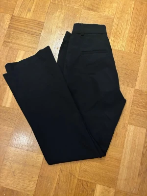 Svarta kostymbyxor från Bik Bok - Snygga  hög midjade svarta kostymbyxor från Bik Bok med klassisk rak passform och diskreta fickor. 