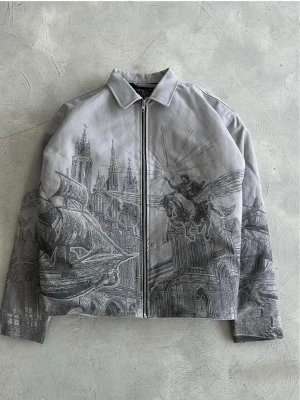 Vescartes Jacka - Unik grå bomberjacka med detaljerat grafiskt tryck av byggnader, skepp och en bevingad figur. Jackan har dragkedja framtill, klassisk krage och lång ärm. Perfekt för dig som vill sticka ut med en konstnärlig vibe. Storlek L men passar som en boxy fit M.