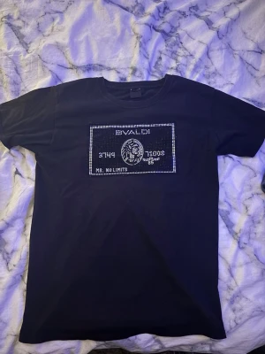 Svart t-shirt med glittrig print - Svart t-shirt från bvaldi  med glittrig print framtill som liknar ett kreditkort. T-shirten har rund halsringning och korta ärmar. Perfekt för dig som vill sticka ut med en unik och snygg detalj på bröstet.