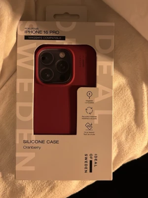 Rött silikonfodral iDeal of Sweden - Snyggt rött silikonfodral för iPhone 16 Pro från iDeal of Sweden. Fodralet är MagSafe-kompatibelt och tillverkat i mjukt silikonmaterial. Färgen heter Cranberry. Säljer pga att jag köpte till fel mobil. Perfekt passform och skydd mot stötar.