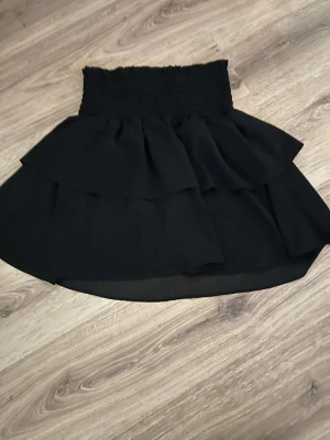 Svart volangkjol - Svart kortkjol med scrunch på midjan. Lappen är borta så vet inte vart den är ifrån eller storlek men funkar som s