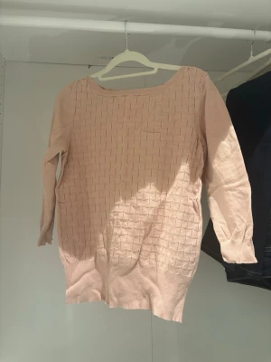 Ljusrosa tröja med struktur - Säljer en ljusrosa tröja med snyggt rutmönster i strukturen. Tröjan har rund halsringning och medellånga ärmar. Perfekt för dig som gillar en enkel men ändå unik look. Materialet känns mjukt och bekvämt.