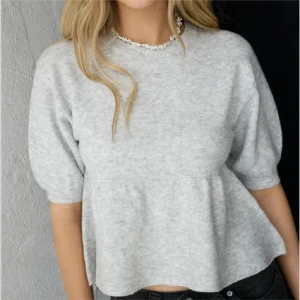 Grå peplum topp med kort ärm - Säljer en ljusgrå peplum topp med rund hals och korta puffärmar från NELLY