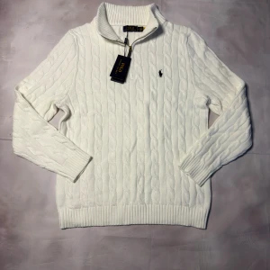 Vit stickad half zip tröja Polo Ralph Lauren - Säljer en vit stickad tröja från Polo Ralph Lauren med half zip och ribbad krage. Tröjan har kabelstickat mönster, långärmad design och den klassiska Polo-loggan broderad på bröstet. Perfekt för dig som gillar clean och stilren look.