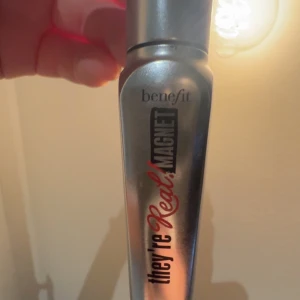 Benefit They're Real! Magnet Mascara💓 - Säljer en mini  Benefit They're Real! Magnet mascara i en snygg silverfärgad tub. Mascaran har en innovativ formula som ger längd och volym till fransarna. Tuben är metallisk och har svart och röd text. Perfekt för dig som vill ha dramatiska fransar.🙃