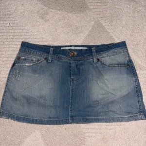 Lågmidjad jeanskjol - Superfin lågmidjad kjol med små broderier på. Säljer på grund av att den inte kommer till användning. 