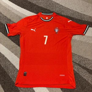 Portugal 2025 Hemmatröja - Säljer nu denna Portugal hemmatröja då den var för liten för mig. Storleken är XXL men det är en autentisk spelar tröja och de är lite tajta och mindre då så den är mer som en XL. Den har RONALDO 7 på ryggen. Denna tröja är perfekt inför VM nästa år.  Vid frågor är det bara att skriva.