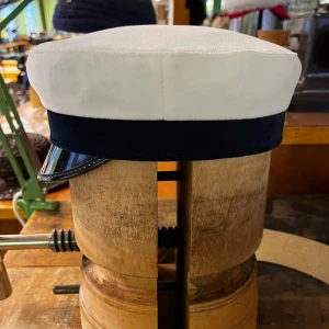 Studentmössa Lunda modell st 52-63 - Klassisk studentmössa från CTH med vit ovandel i bomull, mörkblå band och blank svart skärm. Insidan är fodrad med rött tyg och har en gul blomdetalj med blå mitt på framsidan. Perfekt för studenten och riktigt snygg att bära på din stora dag. Mössan är i Lunda modellen