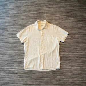 Vit kortärmad skjorta från Solid - Fräsch vit skjorta från Solid i regular fit, perfekt för dig som gillar enkel och clean stil. Skjortan har korta ärmar, klassisk krage, bröstficka och knappar framtill. Materialet är linne, vilket gör den lätt och skön att bära under varma dagar.