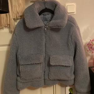Grå teddyjacka från FB Sister - Helt ny mysig grå/ljus blå teddyjacka från New yorker Sister i storlek S. Fleece-liknande material.