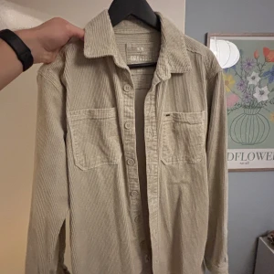 Beige manchester overshirt Only & Sons - Snygg beige overshirt från Only & Sons i mjuk manchester. Skjortan har klassisk krage, två stora bröstfickor och knappar framtill. Perfekt att slänga över en t-shirt för en chill look. Långärmad och loose fit för extra komfort. Inköpt för 500kr för cirka 1 ett år sedan.