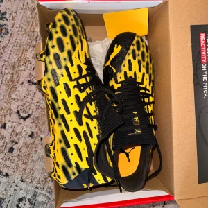 Gula och svarta fotbollsskor Puma (aldrig använda) - Säljer ett par grymma fotbollsskor från Puma med ett iögonfallande leopardmönster i gult och svart. Skorna har snörning och platt sula med dobbar för bästa grepp på planen. Perfekt för dig som vill sticka ut och spela med stil.