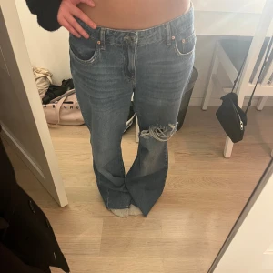 Blå wide jeans med hål på knät - Säljer ett par blå jeans med wide fit och låg midja. Säljer då de inte kommer till användning, även klippta längst ner för o passa mig bättre i längden (är 160). Använda fåtal gånger.