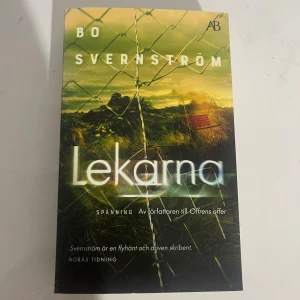 Lekarna - En spännande bok med mystisk stämning, perfekt för dig som gillar nervkittlande berättelser. Omslaget visar ett trasigt stängsel och en tom gunga i solnedgång, vilket ger en känsla av fara och hemligheter. Skriven av författaren till Offrens offer.