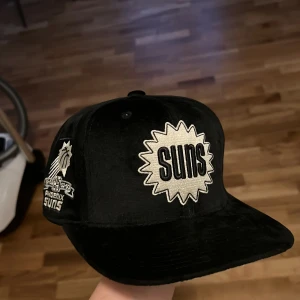 Phoenix Suns keps Mitchell & Ness - Snygg svart keps från Mitchell & Ness med broderade Phoenix Suns-loggor. Velour material för att sticka ut lite extra. Aldrig använd. 
