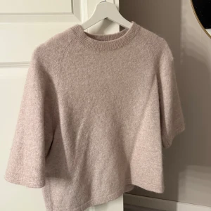 Beige stickad tröja & Other Stories - Supermjuk och fluffig beige stickad tröja från & Other Stories. Tröjan har korta ärmar, rund halsringning och en avslappnad passform. Perfekt för lager-på-lager och ger en chill men ändå stilren vibe.