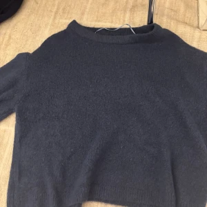 Mörkblå stickad tröja från 157 - Mysig mörkblå stickad tröja från 157 med rund hals och långärmad design. Perfekt för dig som gillar enkel och clean stil. Materialet är mjukt och ger en skön känsla, passar dig som vill ha en basic tröja med lite oversized vibe.