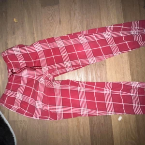 Röda rutiga mjukisbyxor med snörning - Röda mjukisbyxor med vitt rutmönster och snörning i midjan. Perfekta för chill dagar hemma eller när du vill vara extra bekväm. Mjukt material och avslappnad passform.