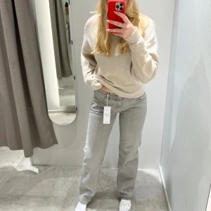 Grå raka jeans med low waist  - Säljer ett par grå jeans med rak passform och låg midja. Jeansen har klassisk femficksdesign och är tillverkade i mjukt denimtyg. Perfekta för dig som gillar en avslappnad och stilren look.