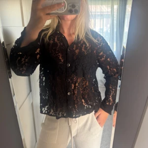 Svart spetsblus med knappar - Säljer en svart blus i spets med knappar framtill. Kan även ha den som en kofta. Ny med prislapp, nypris 400 kr