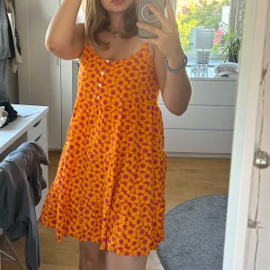 Klänning - Säljer en färgglad orange och rosa klänning med blommigt mönster! Den är klart för liten för mig och därför säljer jag den! Aldrig används. Storlek S! Skriv om du har frågor eller undrar något!💖