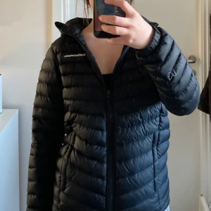 Svart dunjacka från Peak Performance - Säljer en svart dunjacka från Peak Performance i storlek XS. Jackan har lång ärm, dragkedja framtill och klassisk pufferdesign. Perfekt för kyliga dagar och enkel att matcha med olika outfits.