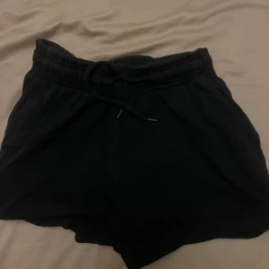 Svarta shorts med snörning - Svarta shorts med elastisk midja och snörning framtill. De är enkla och bekväma, perfekta för chill dagar eller träning. Mjukt material och loose fit gör dem riktigt sköna att ha på sig.
