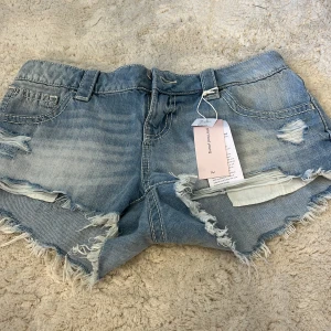 Ljusblåa xtra low denim shorts Gina Tricot - Jag säljer dessa slutsålda jeansshorts från Gina Young 14+. Ljusblåa jeansshorts från Gina Tricot i extra låg midja. Råa, fransiga kanter och slitna detaljer framtill ger en cool vibe. Klassiska fickor fram och bak, med dekorativa sömmar på bakfickorna. Perfekta för sommaren och festivaler. Priset kan diskuteras.