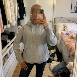 Grå hoodie från FB Sister med huva - Säljer en ljusgrå superskön hoodie från FB Sister i storlek XS. Tröjan har en klassisk huva med snörning, stor magficka och ribbade muddar vid ärmslut och nederkant. Perfekt för chill dagar och enkel att matcha med jeans eller leggings.