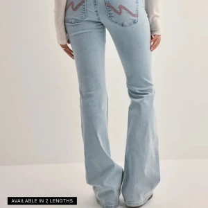 Ljusblå bootcut jeans med slitningar - Säljer ett par ljusblå bootcut jeans med snygga slitningar över knäna och broderade detaljer på bakfickorna. Jeansen har låg midja och är tillverkade i klassisk denim. Perfekta för dig som gillar en avslappnad men trendig look. Ganska slitna vid fötterna skriv privat för bilder 