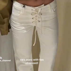 Vita jeansbyxor med snörning från Zara - Säljer ett par vita jeansbyxor från Zara med snygg snörning framtill i midjan. Byxorna har raka ben och låg midja, klassisk femficksdesign och coola detaljer som gör dem unika. Storlek 34 