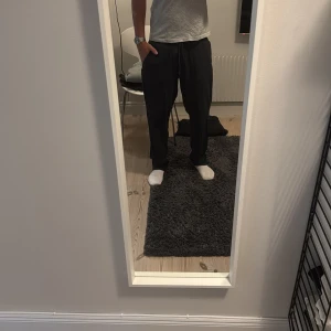 Svarta linnebyxor med snörning - Svarta linnebyxor med elastisk midja och snörning. Byxorna har en loose passform och är tillverkade i mjukt material, perfekta för chill dagar. Fickor på sidorna och enkel stil som funkar till det mesta.