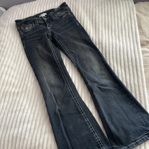 Bootcut jeans från Gina Tricot, svart - Snygga svarta bootcut jeans från Gina Tricot i storlek 146. Fint skick. Jeansen har kontrastsömmar, klassiska fem fickor och coola detaljer med knappar på bakfickorna💘