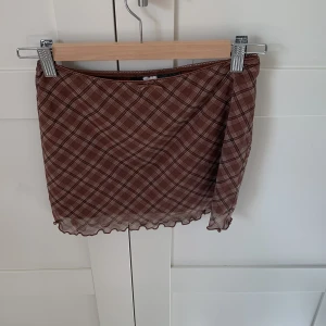 Brun rutig kortkjol från H&M Divided - Brun rutig kortkjol från H&M Divided i storlek XS. Kjolen är i bra skick.