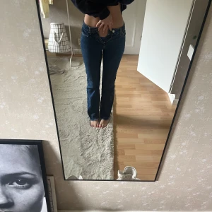 Mörkblå jeans bootcut - Jeans i mörkblå denim med bootcut. Mid waiste och raka ben som går ut lite nertill. Snygga kontrastsömmar och femficksmodell. Perfekta till sneakers eller boots. Ikonisk läderpatch bak i midjan. Helt ny skick