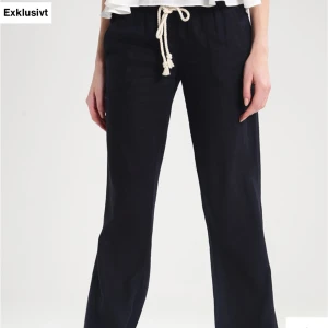 Svarta linnebyxor med snörning - Snygga svarta linnebyxor med avslappnad passform och vit snörning i midjan. Byxorna har raka ben och elastisk midja för extra komfort. Perfekta för en chill och stilren look.