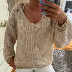 Stickad tröja! - Säljer en beige stickad tröja med v-ringning och långa ärmar. Tröjan har en loose och oversized passform med ribbade muddar i guld. Perfekt för lager-på-lager och chill vibes. Står ingen storlek i