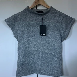Grå mock neck topp från Pieces - Jättefin topp från Nelly i nyskick! Storlek L men passar mig som bär S/M i tröjor. Säljer då jag råkade beställa två stycken! Ordinarie pris 399.