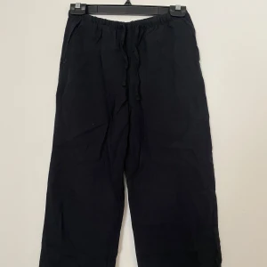 Svarta linnebyxor från Gina Tricot - Svarta linnebyxor från Gina Tricot med avslappnad passform och snöre i midjan. Byxorna är tillverkade i en skön linneblandning och har elastisk midja för extra komfort. 