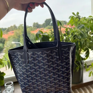 Blå  handväska med mönster - Säljer en blå handväska från en marknad  i Spanien.  Väskan har två handtag, vita kontrastsömmar och medföljande matchande plånbok. Aldrig använd🥰 Detta är den lilla modellen