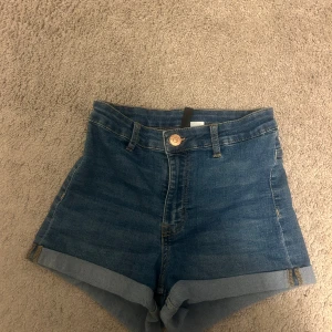 Blå högmidjade jeansshorts - Snygga blå jeansshorts med hög midja och uppvikta benslut. Storlek s men tycker den passar mer xs.