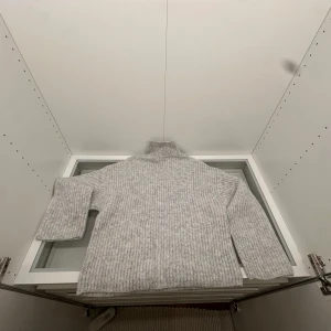 Ljusgrå polotröja från Gina Tricot - Säljer en ljusgrå, ribbstickad polotröja från Gina Tricot i storlek S. Tröjan har en hög och bred polokrage, långärmade och loose fit. Materialet är mjukt och består av Polyana-fiber som ger en ullig känsla. Perfekt för dig som gillar chill och stilren vibe.