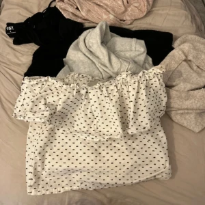 Vit offshoulder topp med prickar - Supersöt vit offshoulder topp med små svarta prickar och volang upptill. Perfekt för dig som gillar en romantisk och trendig stil. Tunn och luftig, passar perfekt till jeans eller kjol.